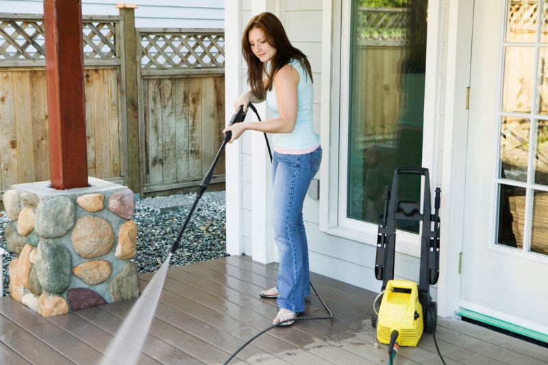 Una donna pulisce la terrazza con alta pressione