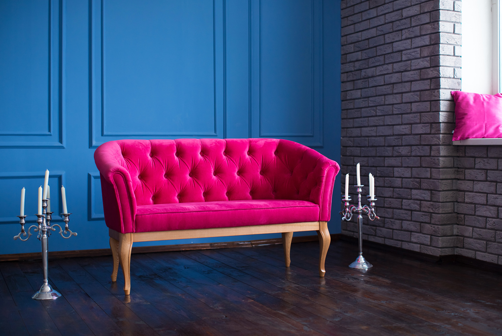 Ein pinkfarbenes Sofa vor einer blauen Wand