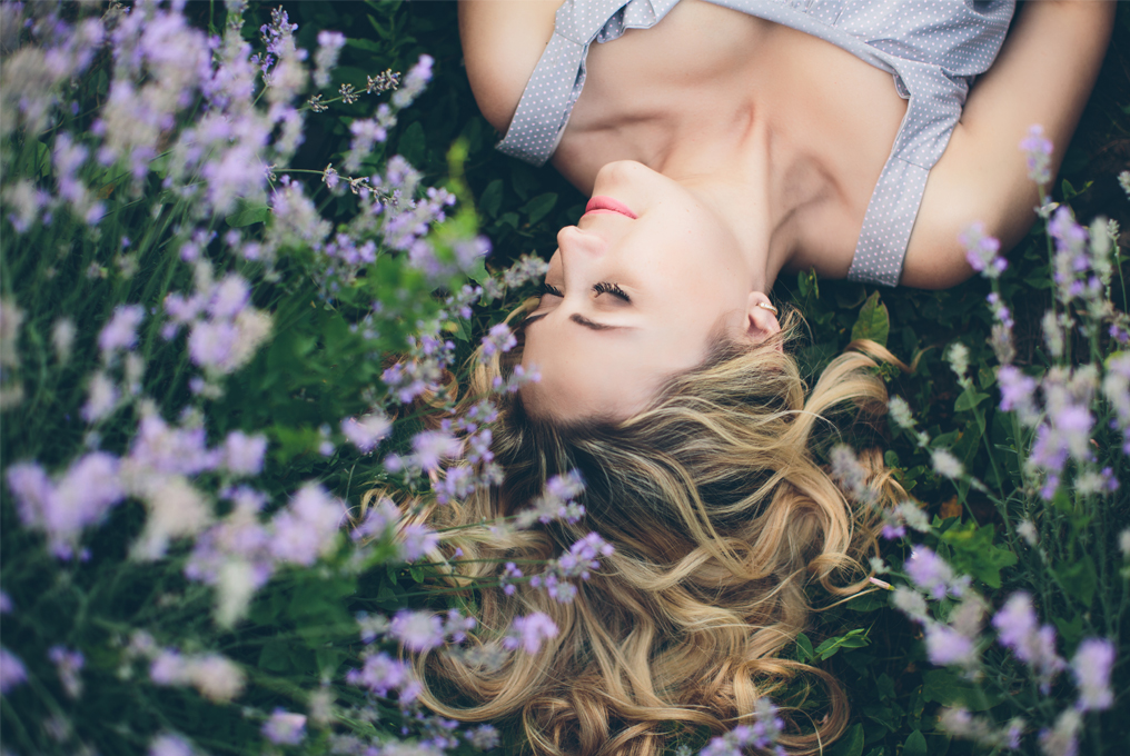 Eine Frau liegt auf einer Wiese zwischen Lavendel.