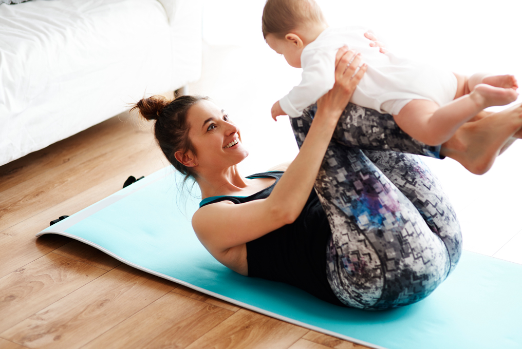 Una donna sul tappetino che fa sport con il suo bambino