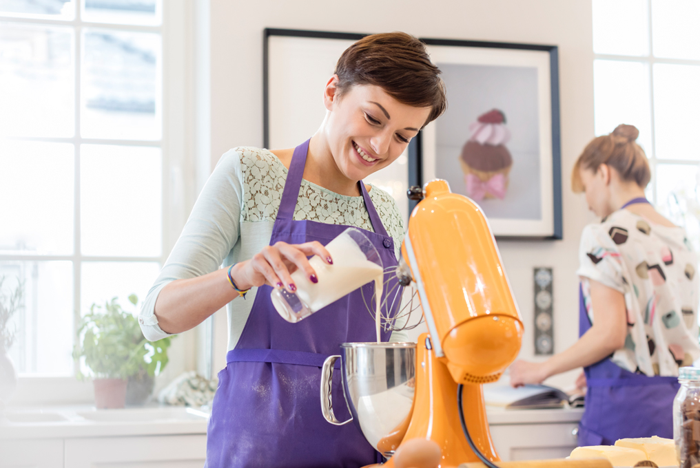 Due donne sono in cucina a mescolare qualcosa.