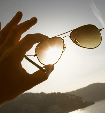 Une main tient des lunettes contre le soleil