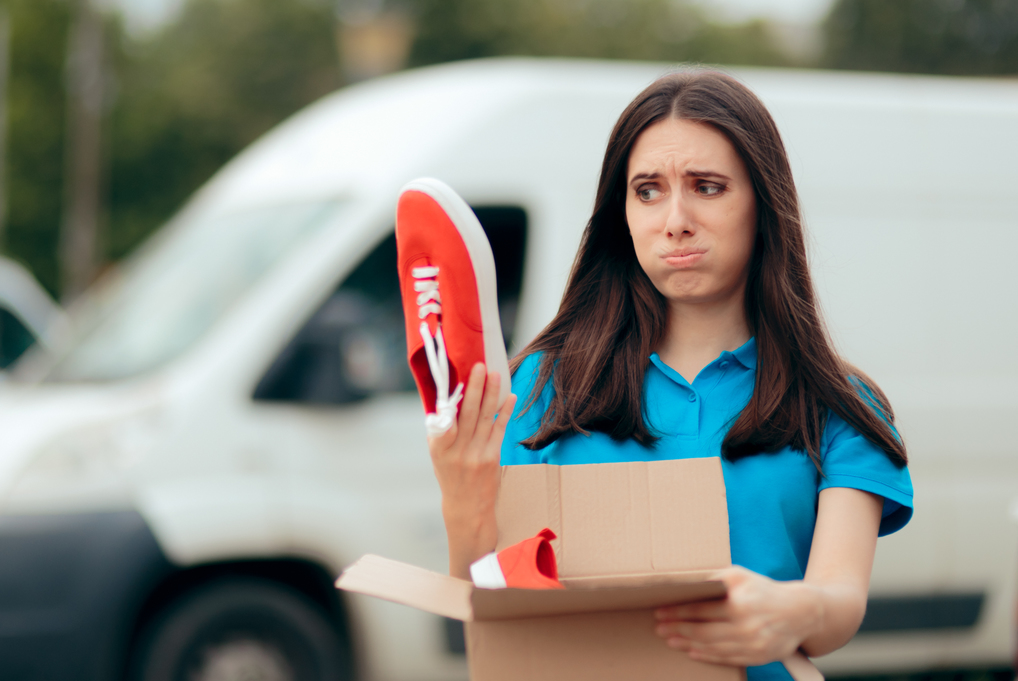 Femme avec un colis contenant des baskets rouges