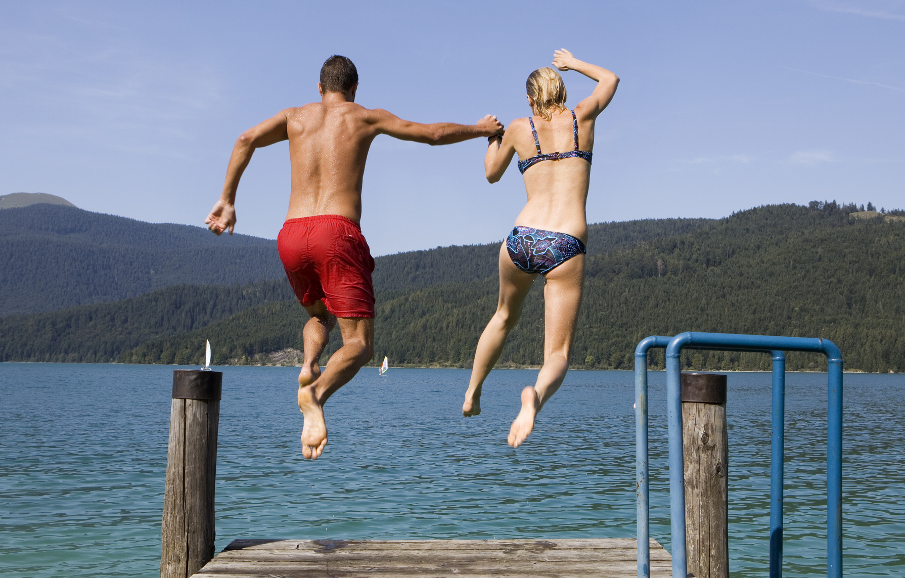 Couple sautant dans un lac depuis un ponton